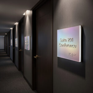 Row of iridescent ADA signs mounted beside office doors along a dim corporate hallway.